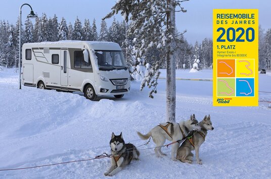 Integriertes Mobil HYMER Exsis-i und Schlittenhunde in winterlicher Landschaft mit Auszeichnung Reisemobil des Jahres 2020
