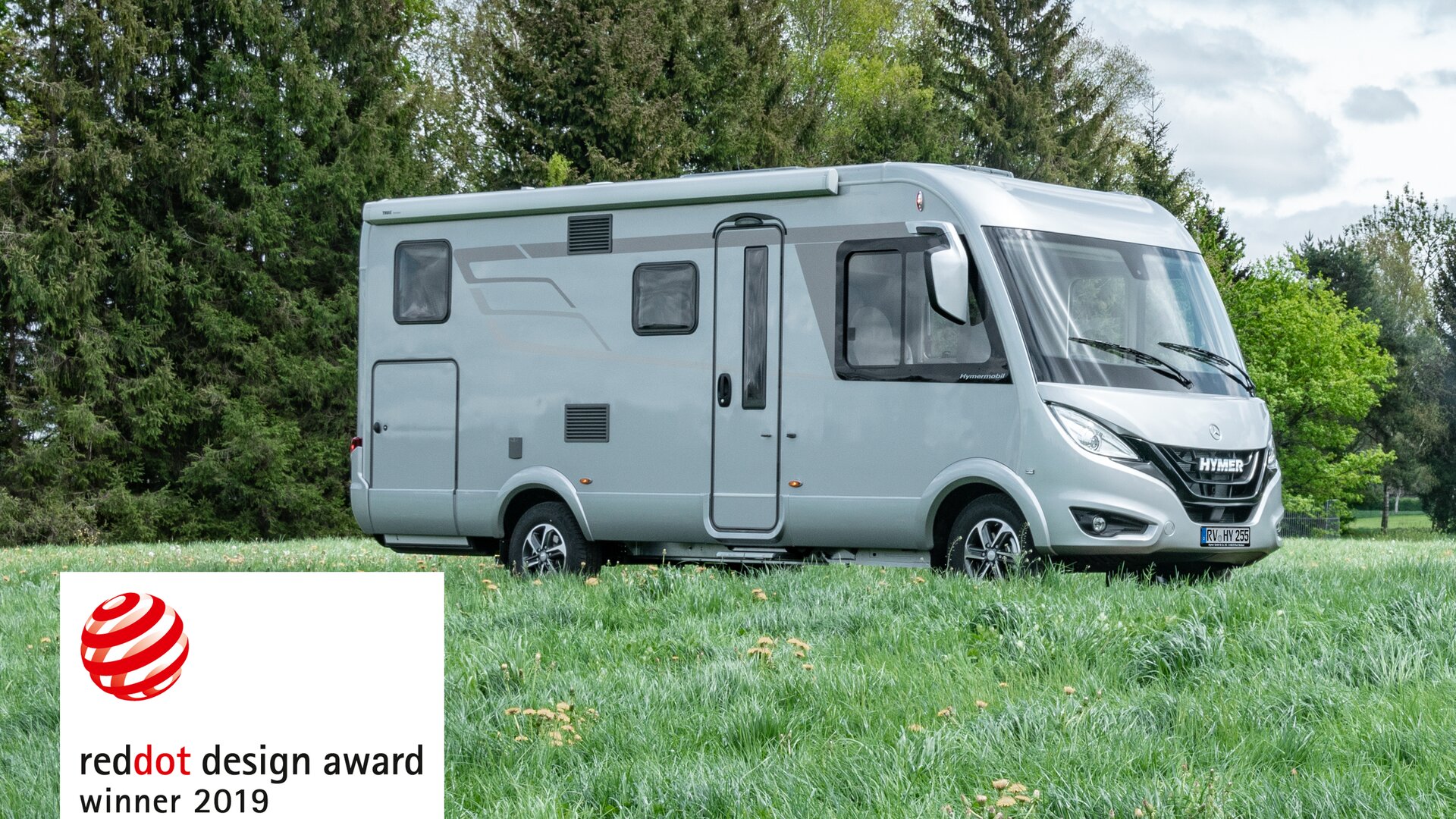 HYMER B-MC I WhiteLine standing on a meadow with trees in the background and emblem Reddot Design Award Winner 2019