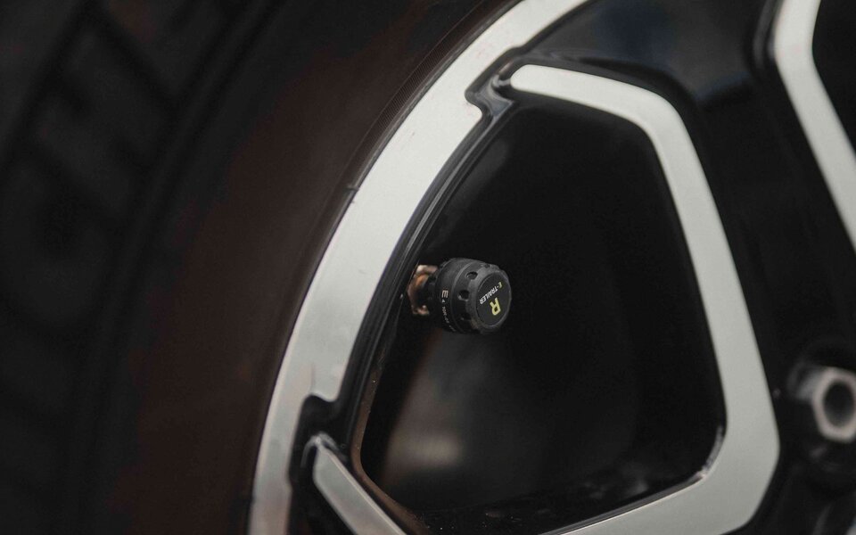Close-up of a sensor valve cap on a tire on a black-silver aluminium rim	