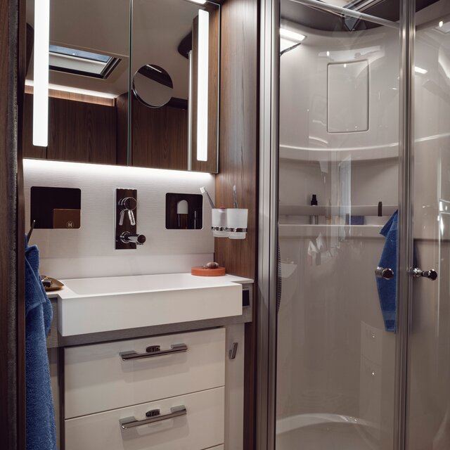 Bathroom in the HYMER B-ML I 890: illuminated mirror cabinet, drawers under the washbasin, separate shower with real glass doors