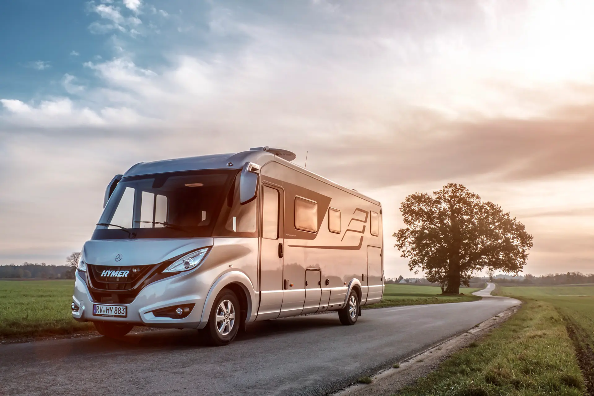 HYMER B-Klasse Masterline auf Straße in ebener Landschaft mit grünen Wiesen und Bäumen