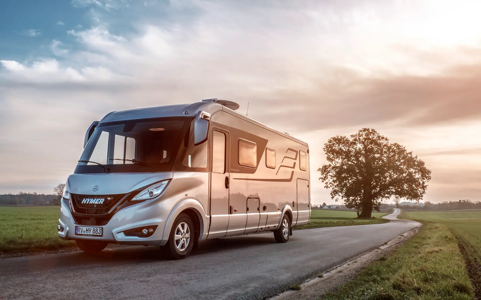 HYMER B-Klasse Masterline auf Straße in ebener Landschaft mit grünen Wiesen und Bäumen