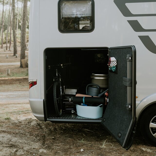Rear garage of a HYMER motorhome loaded with bicycles, watering cans, Isomats, etc