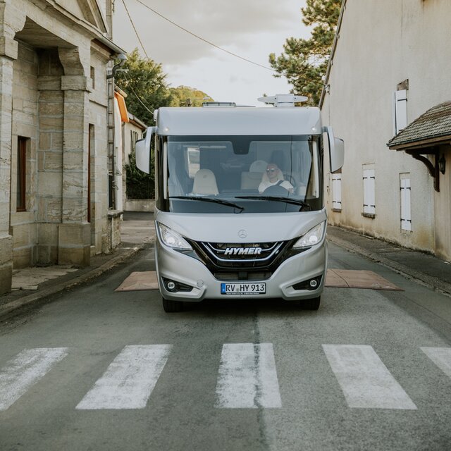 Front view of a fully integrated HYMER B-ML I motorhome in front of a zebra crossing in a town