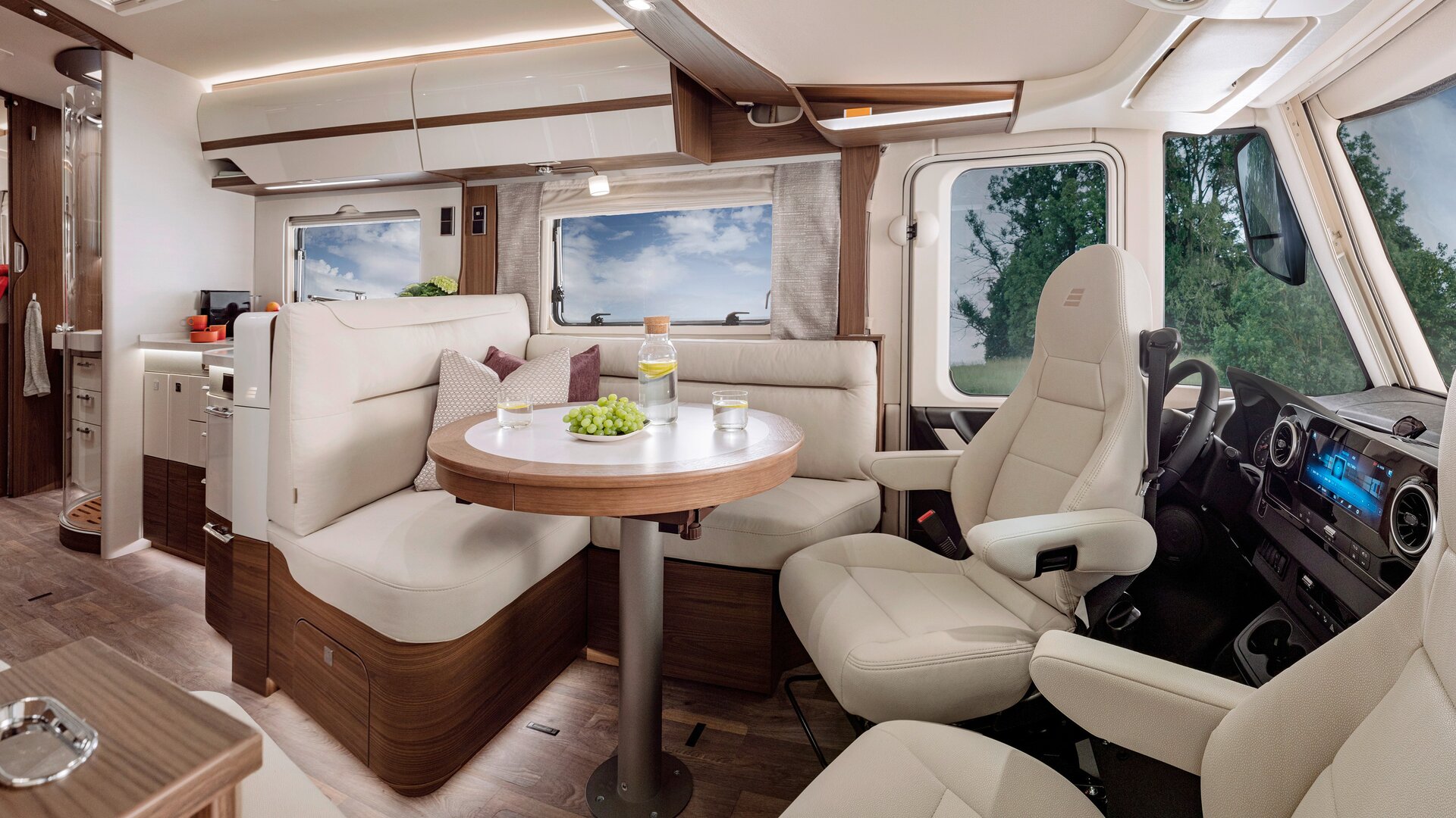 Wohnraum im HYMER-B-MasterLine mit Sitzmöglichkeit in cremefarbener Lederoptik am runden Tisch