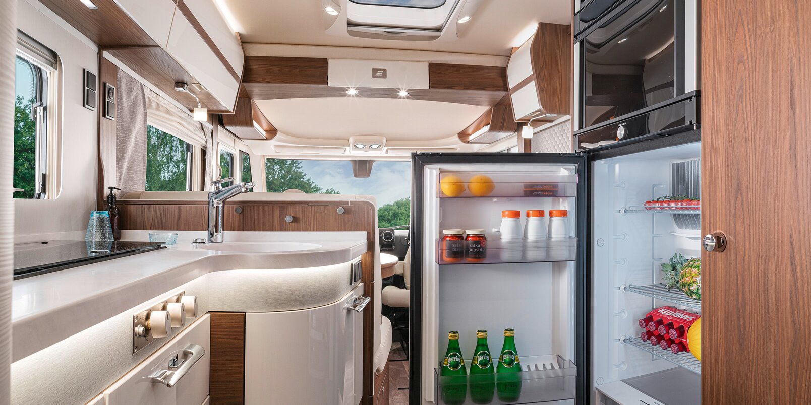 Filled, open refrigerator opposite the kitchen work surface in the HYMER B-ML I 880