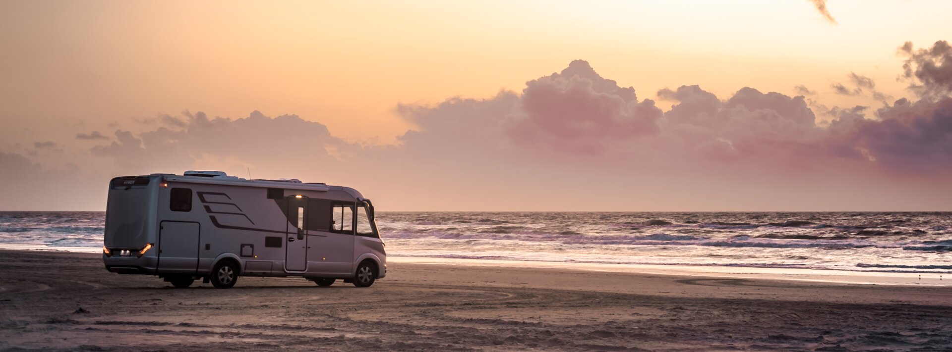 HYMER B-Class MasterLine I by the sea on a sandy beach with sunset