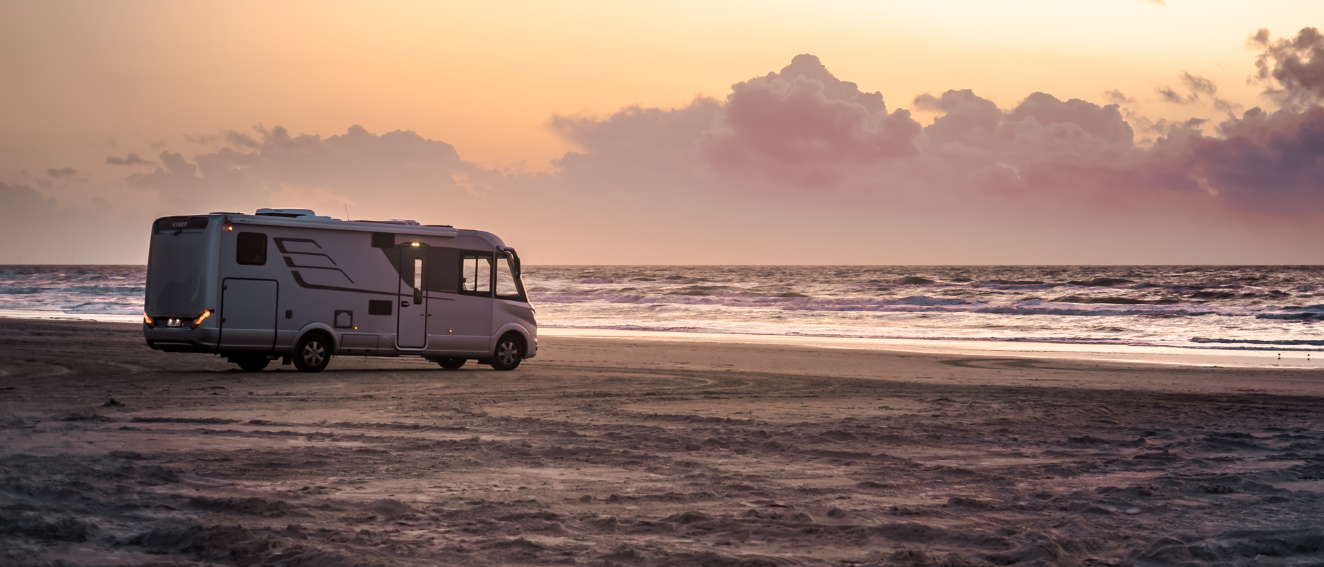 HYMER B-Class MasterLine I by the sea on a sandy beach with sunset