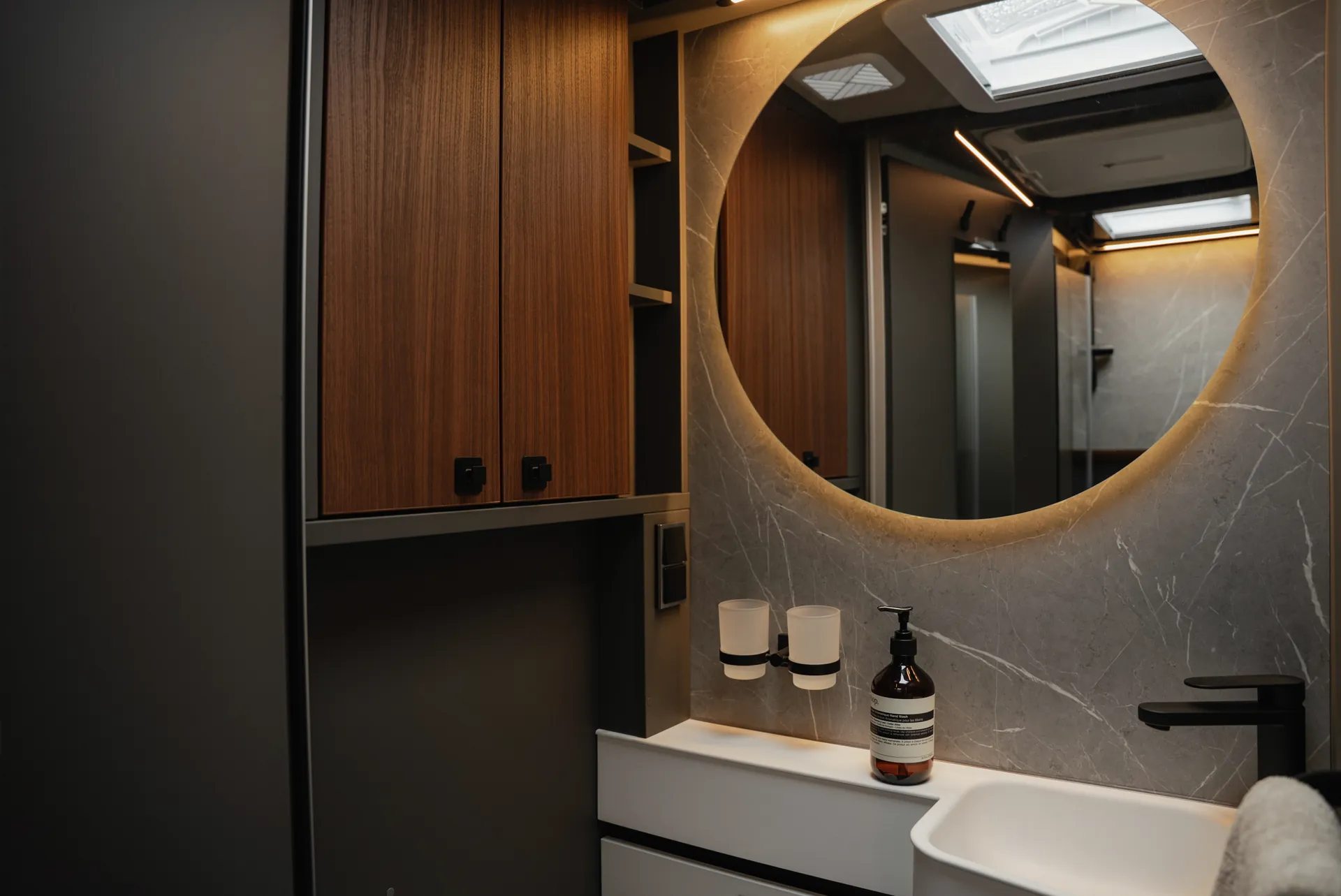Le miroir rond éclairé, les surfaces haut de gamme et les détails précis créent une atmosphère qui associe harmonieusement convivialité et qualité.