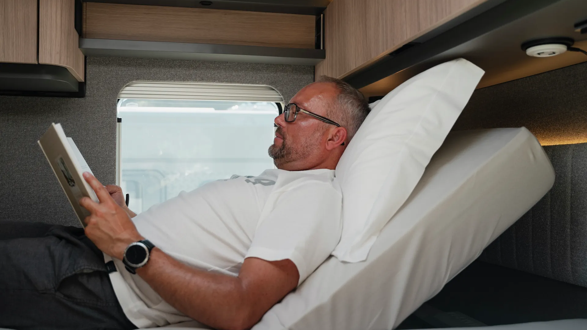 Lire, se détendre, arriver : le système de tête de lit à réglage électrique adapte individuellement la position de repos. Disponible via Hymer Original Parts.