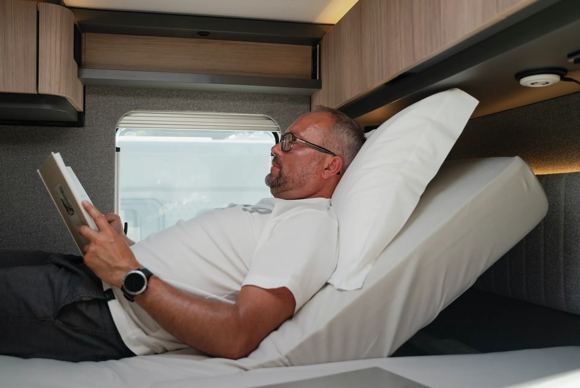 Lire, se détendre, arriver : le système de tête de lit à réglage électrique adapte individuellement la position de repos. Disponible via Hymer Original Parts.