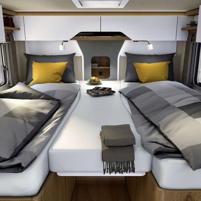Lengthways single beds with gray checked bed linen, yellow decorative pillows and central additional cushion in the rear of the HYMER B-ML I