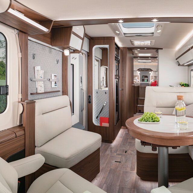 Living room in the HYMER-B-MasterLine with a cream-colored leather look seating area and round table
