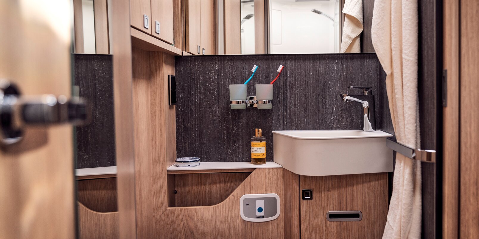 Daylight bathroom with storage space, wash basin; Towel holder, mirror, coat hook and toilet in the HYMER B-ML T