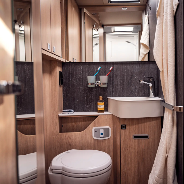 Daylight bathroom with storage space, wash basin; Towel holder, mirror, coat hook and toilet in the HYMER B-ML T
