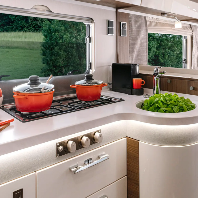 Kitchen with hob and two red pots, sink filled with lettuce and coffee machine in the HYMER MasterLine