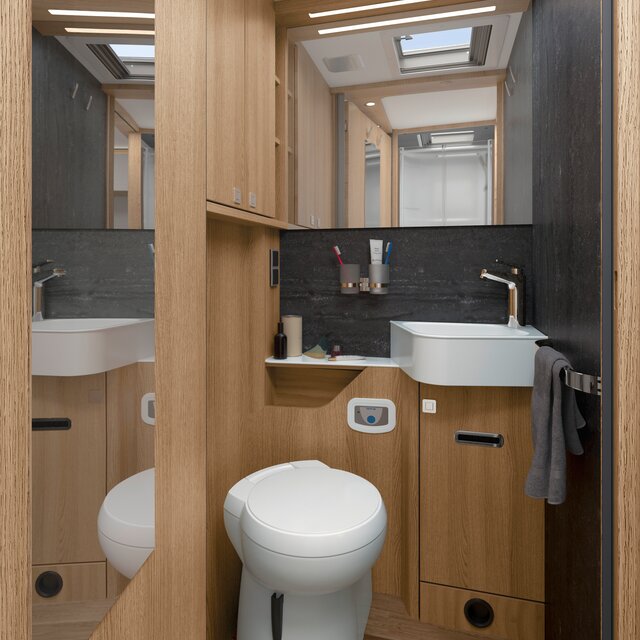 Daylight bathroom with storage space, wash basin; Towel holder, mirror, coat hook and toilet in the HYMER B-ML T