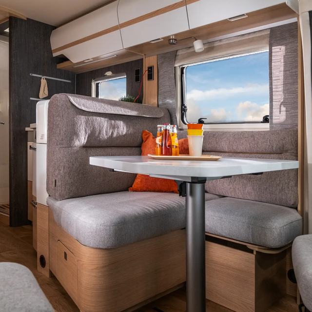 View from the covered seating area and kitchen block through the windows of the HYMER B ML-T 780 of the sunny blue sky