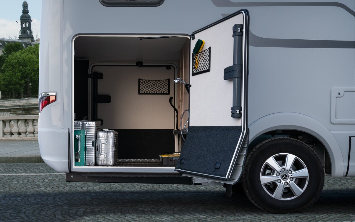 The door of the rear garage of the HYMER B MasterLine is open and is loaded with two silver suitcases