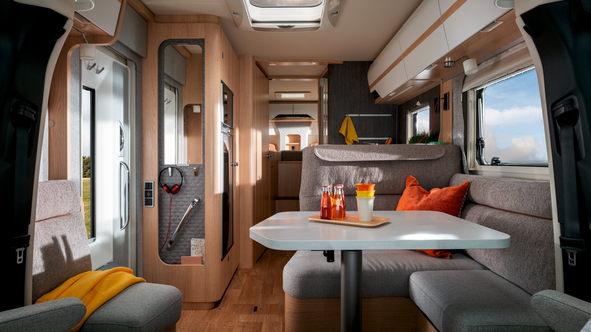 Im Mercedes Sprinter Wohnmobil HYMER B-Klasse MasterLine T mit Oberlicht stehen Getränke und Becher auf dem Tisch, die Sitzgruppe ist grau gepolstert.