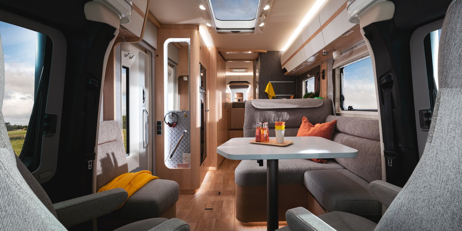 Visione interna dello spazio abitativo, dai sedili in cabina guida, la dinette, fino al letto posteriore dell’HYMER classe B MasterLine T 780