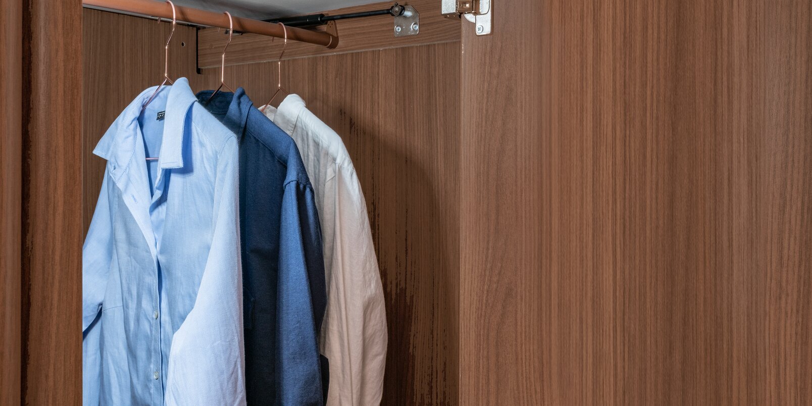 Geopende, verlichte kledingkast met 3 overhemden op de kledingroede in de HYMER MasterLine