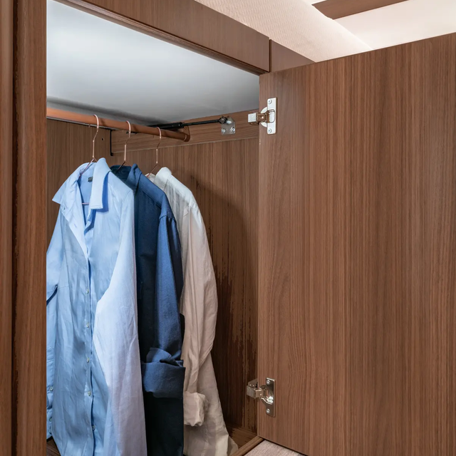 Opened, illuminated wardrobe with 3 shirts on the clothes rail in the HYMER MasterLine