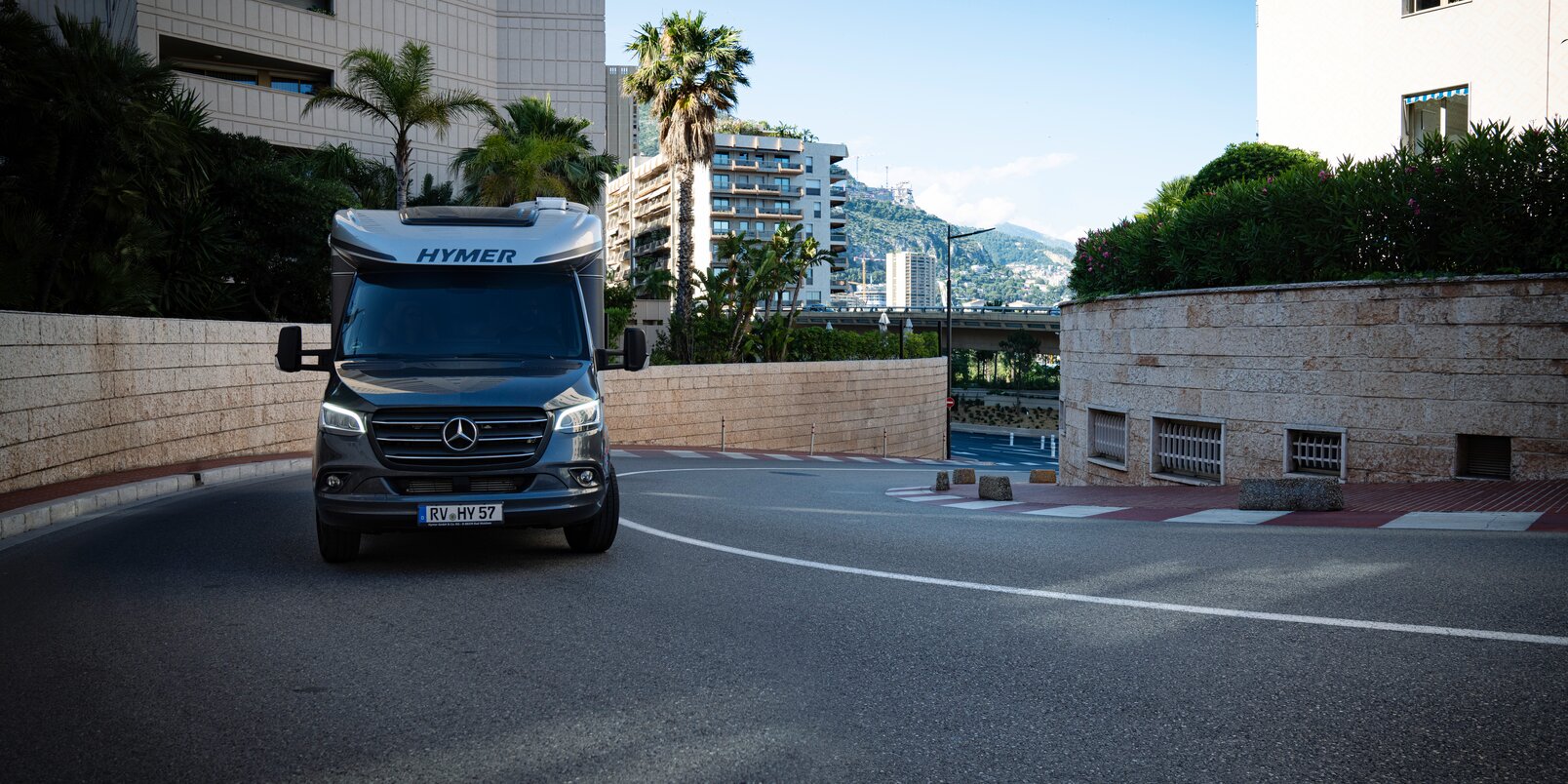 Gorge of houses in a Mediterranean coastal town with a HYMER B-ML T driving uphill in a street curve