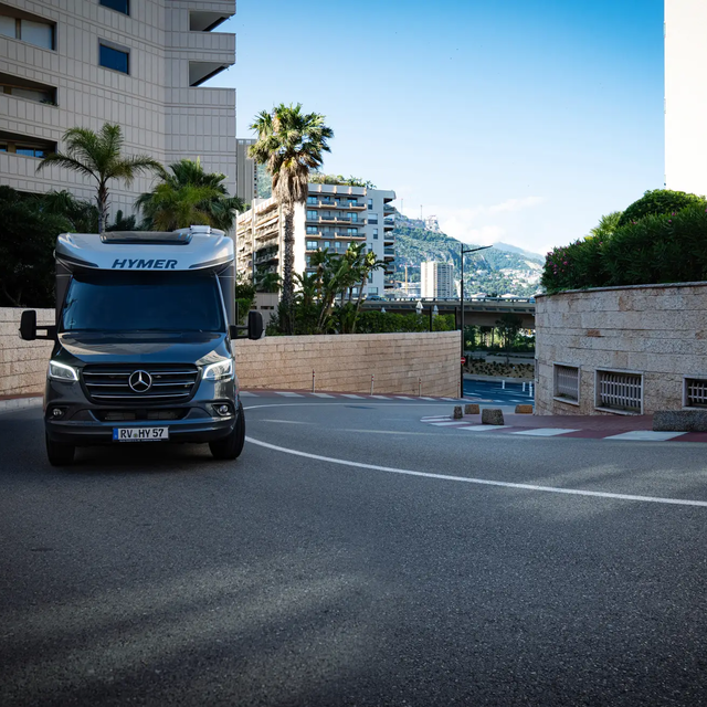 Gorge of houses in a Mediterranean coastal town with a HYMER B-ML T driving uphill in a street curve