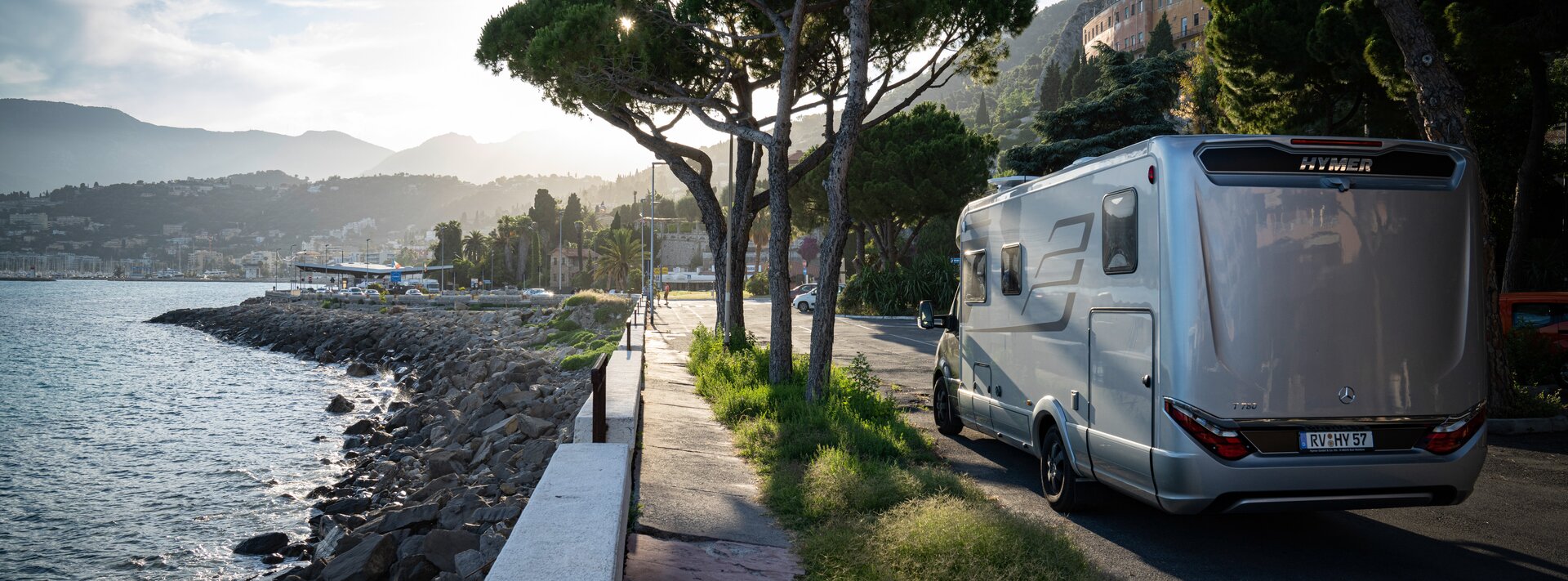 HYMER MasterLine on tree-lined street in a city with a Mediterranean coastal landscape