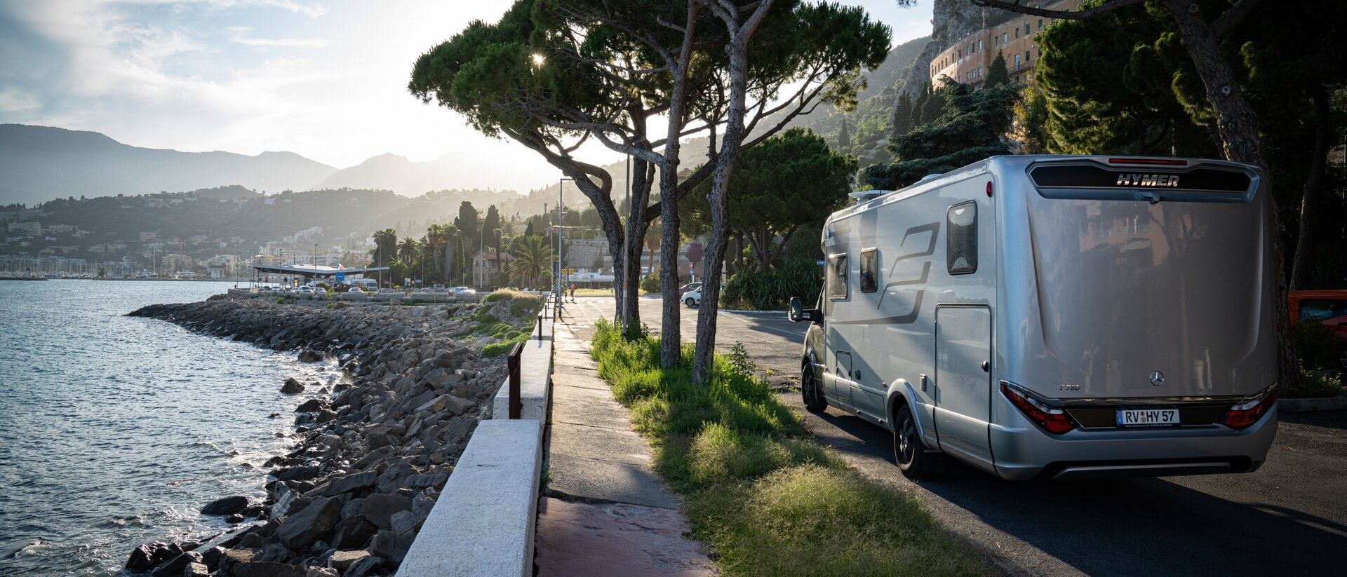 HYMER MasterLine on tree-lined street in a city with a Mediterranean coastal landscape