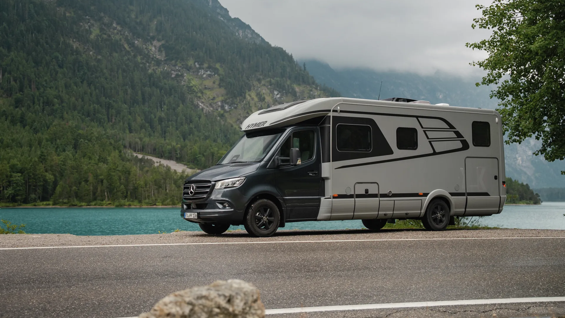 Hymer B‑ML T in front of an impressive mountain and lake landscape with distinctive exterior design and Mercedes‑Benz base vehicle