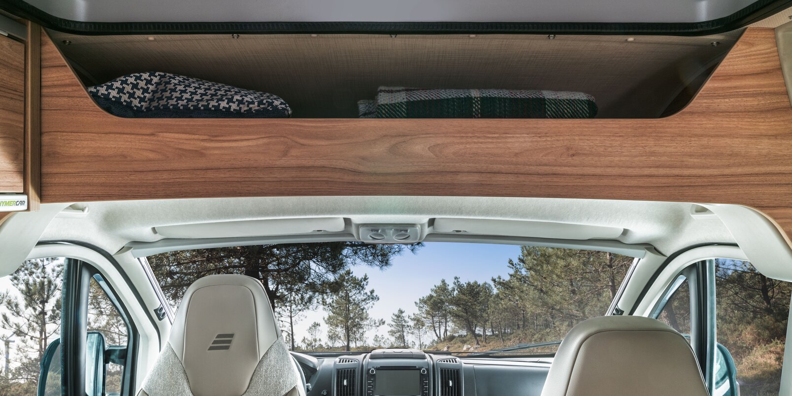 Ruime opbergruimte boven de bestuurderscabine met dekens, bestuurdersstoelen en dashboard in de HYMER Fiat-camper