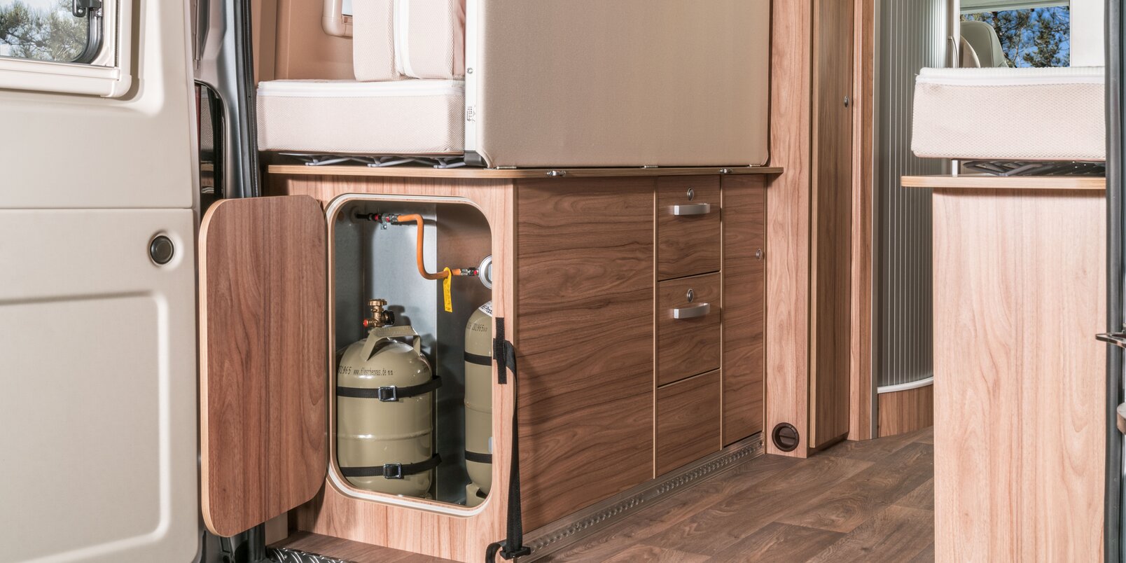 Opened gas bottle locker in the rear under the bed area, storage cupboards and mattresses in the HYMER Camper Van