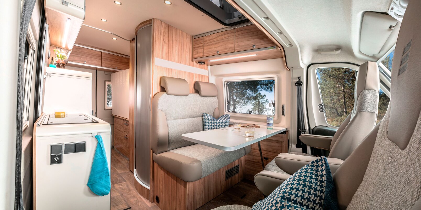Bestuurdersstoelen, tafel, zitbank, bovenkasten, keuken en koelkast in de HYMER CamperVan Fiat