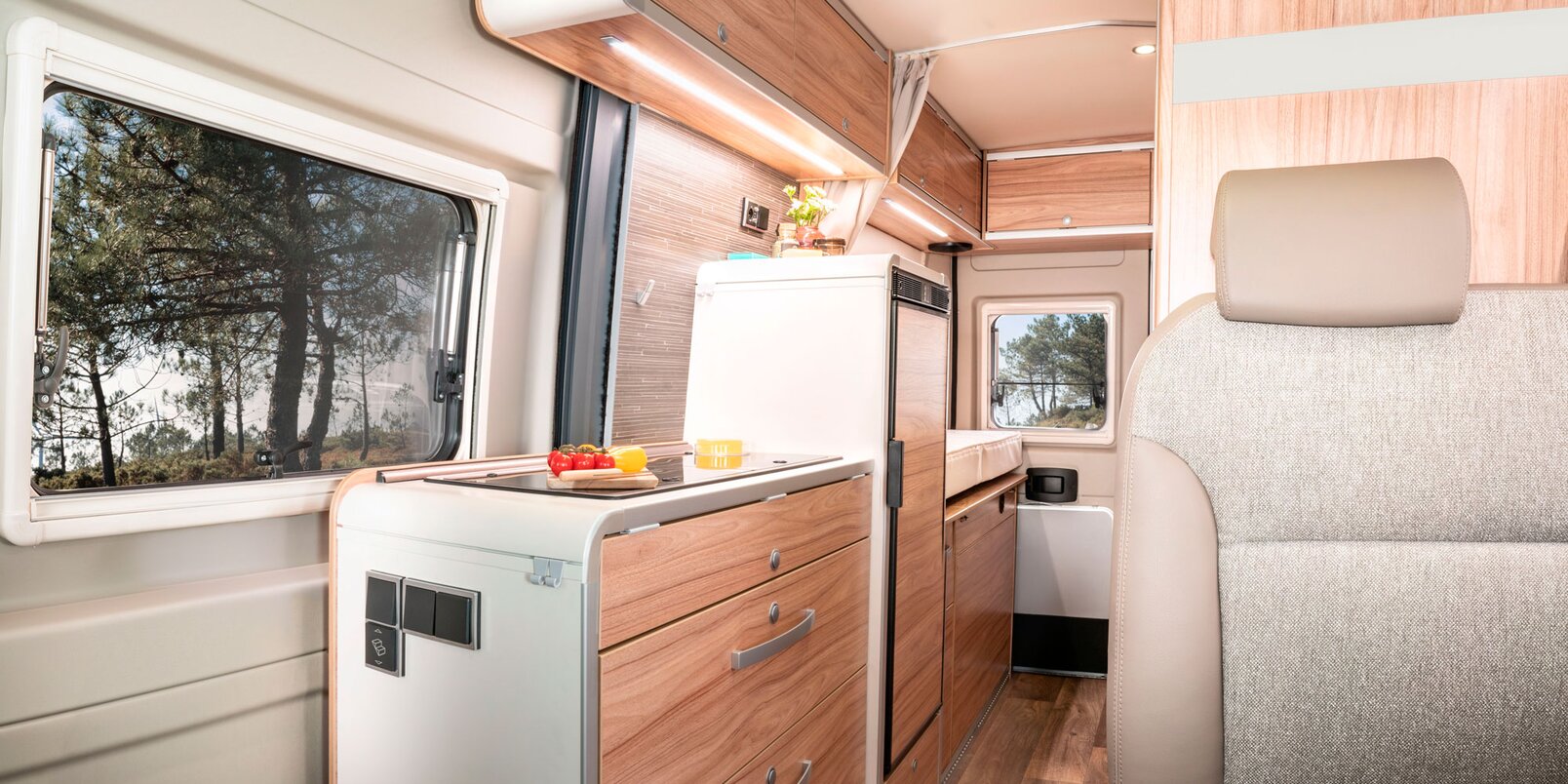 Bench, entrance door, kitchen area with refrigerator and storage cupboards in the HYMER Fiat Camper Van