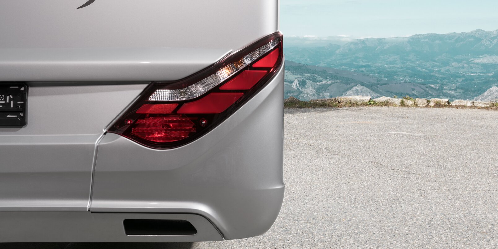 Rear light on the right of the HYMER Exsis-i, which is in a parking lot with a mountain panorama