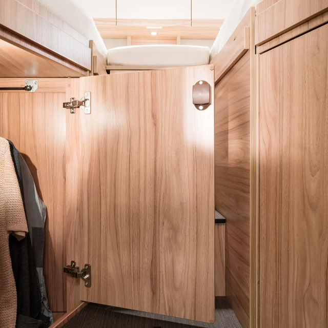 Illuminated wardrobe under the lengthways single bed in the HYMER Exsis-t with top sections on the bar