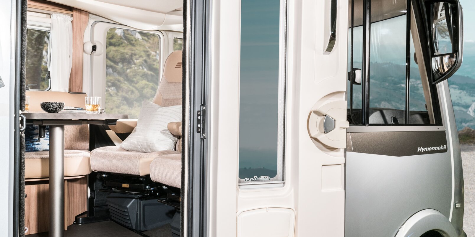 Open entrance door with window and integrated rubbish bin with a view of the seating area in the HYMER Exsis-i