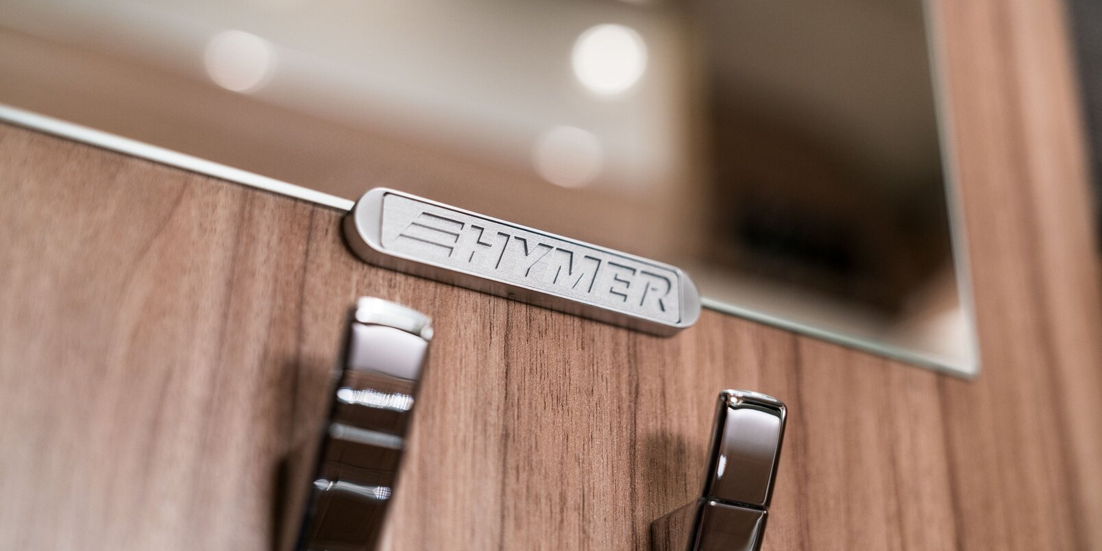 Two coat hooks with the HYMER lettering on the wall unit on the Exsis-i 588