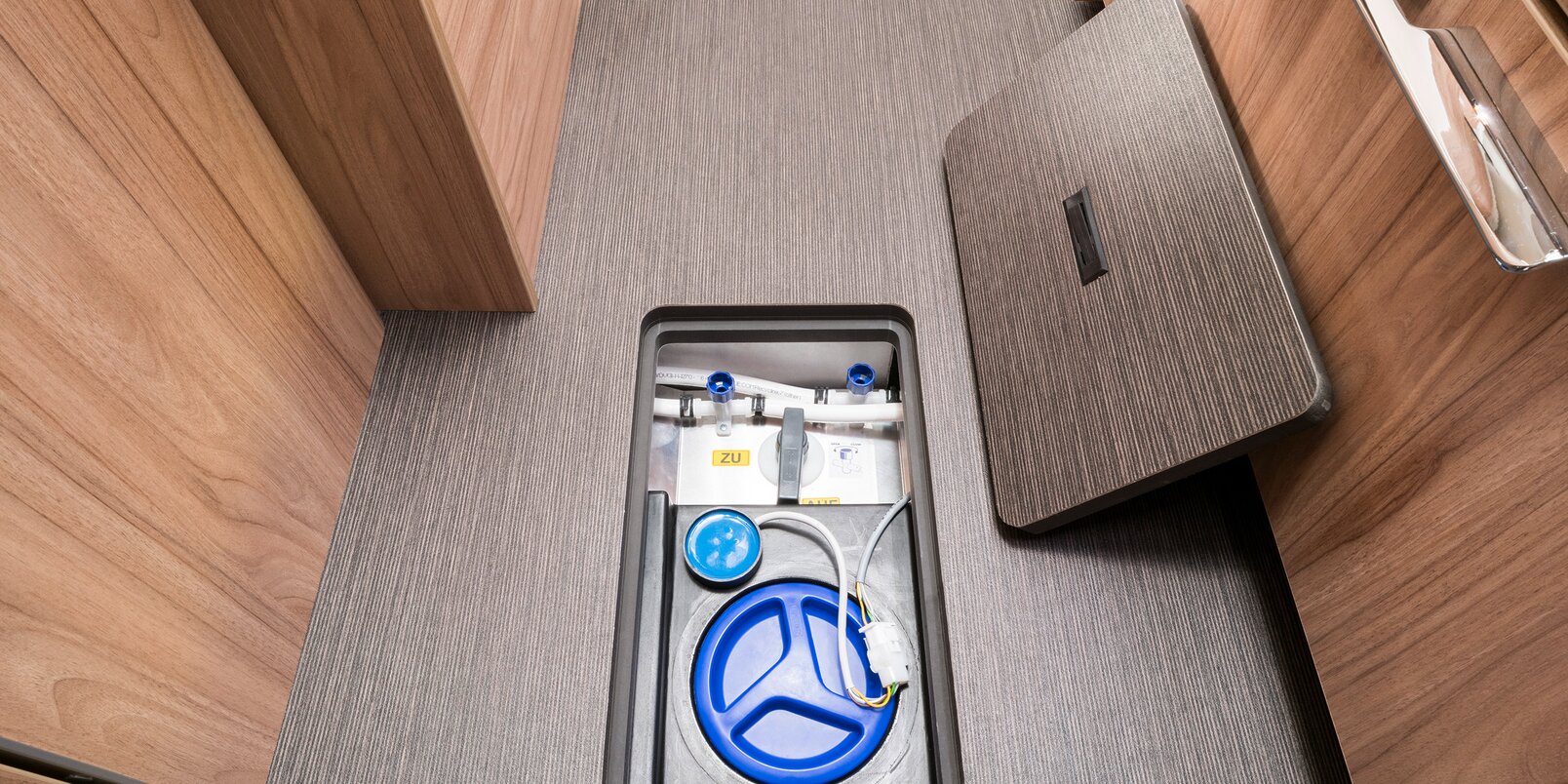 Storage compartment for fresh water tank in the HYMER Exsis that is open from the living area