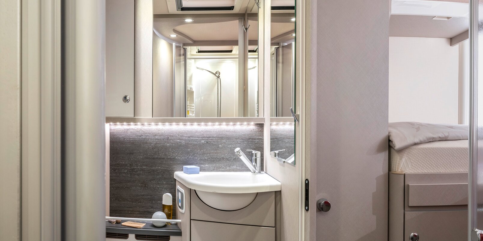 Bathroom in the HYMER Exsis-i 678 with toilet, wash basin, storage cupboards, mirror, and skylight
