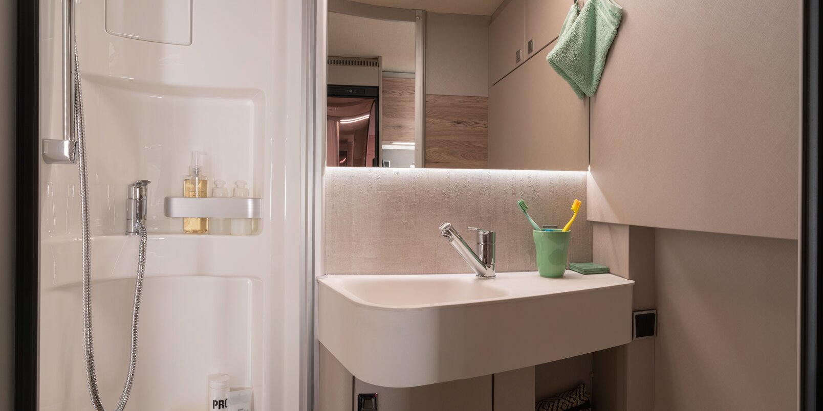 Comfortbadkamer met douchecabine, wastafel, spiegel, opbergkast en badkameraccessoires in de HYMER Exsis 580