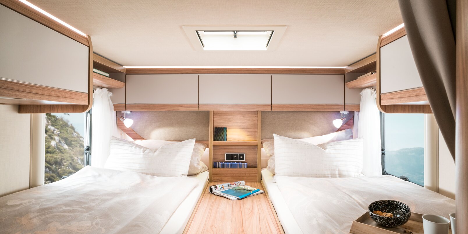 Schlafbereich im HYMER-Exsis t: Bezogene Längseinzelbetten, mittige Ablage, Dachstauschränke im Heck, Beleuchtung