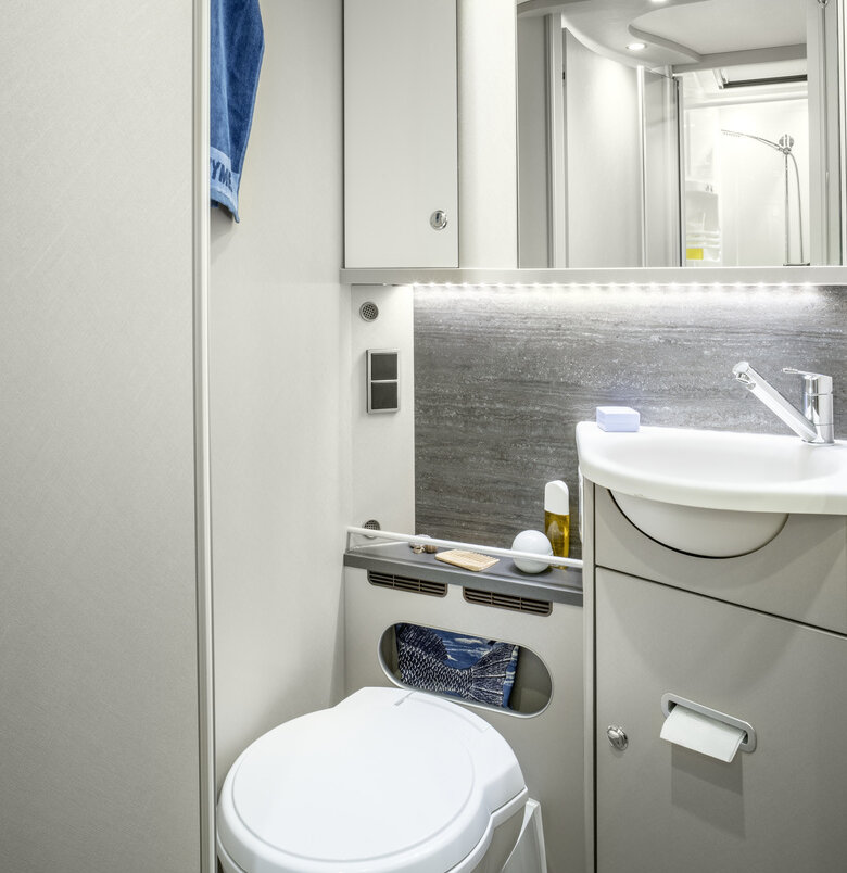 Bathroom in the HYMER Exsis-t with toilet, washbasin, mirror, storage cupboards, skylight