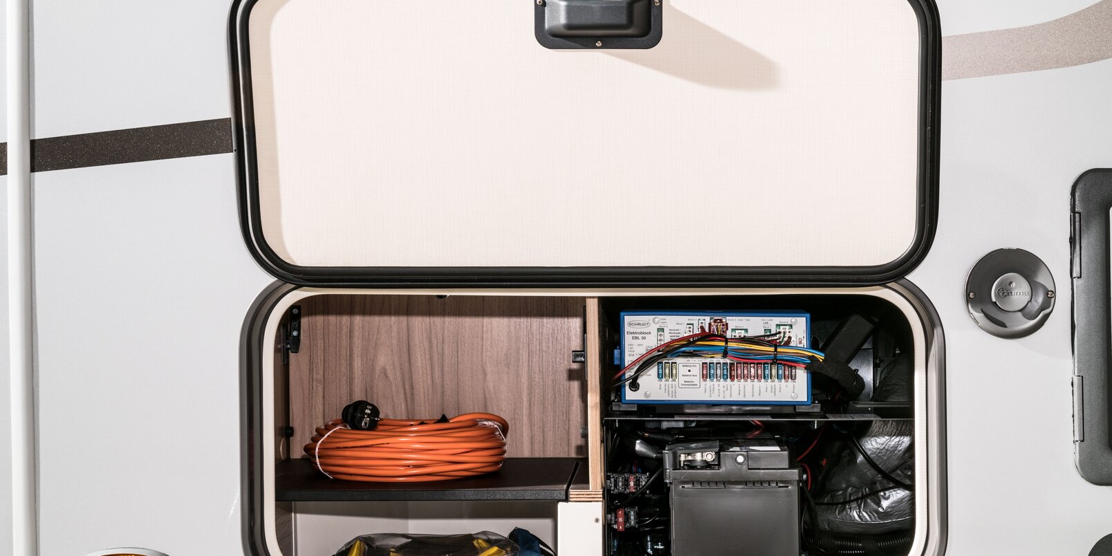 Exterior storage compartment with open flap for living area battery and electroblock on the HYMER Exsis-t