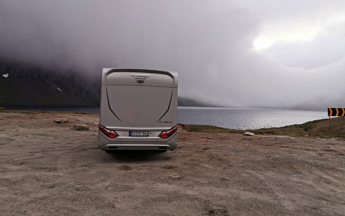 HYMER Exsis-t motorhome from behind on the gravelly shore in a cloud-covered fjord