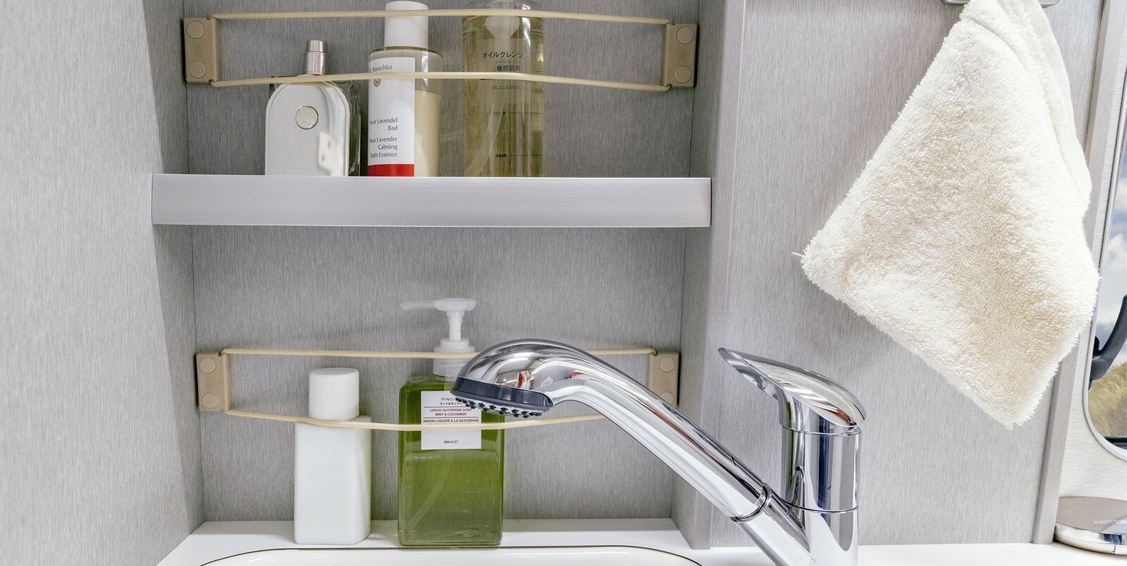 Lavabo, compartimentos de almacenamiento llenos de correas de amarre y accesorios de baño, toallas en el baño con HYMER Free S