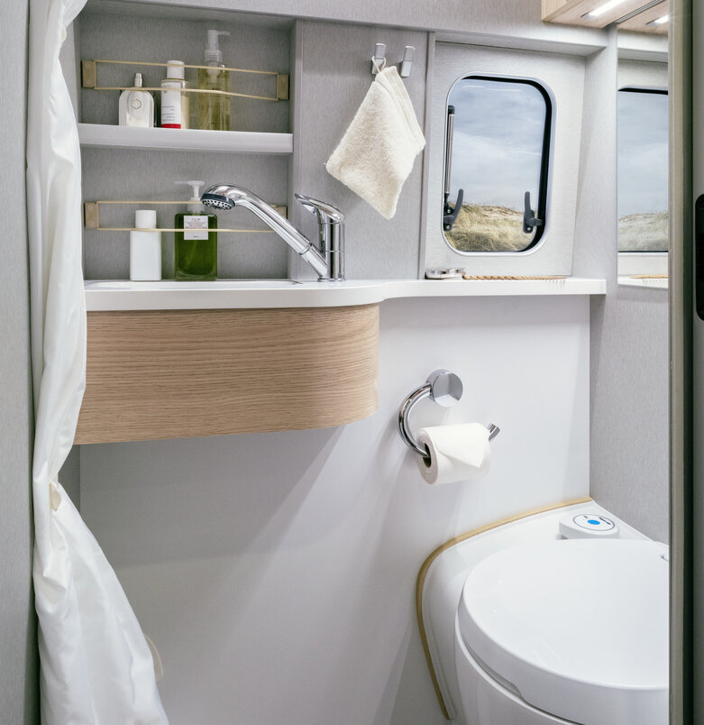 Badkamer met toilet, wastafel en opbergvakken met keukengerei in de HYMER Free S