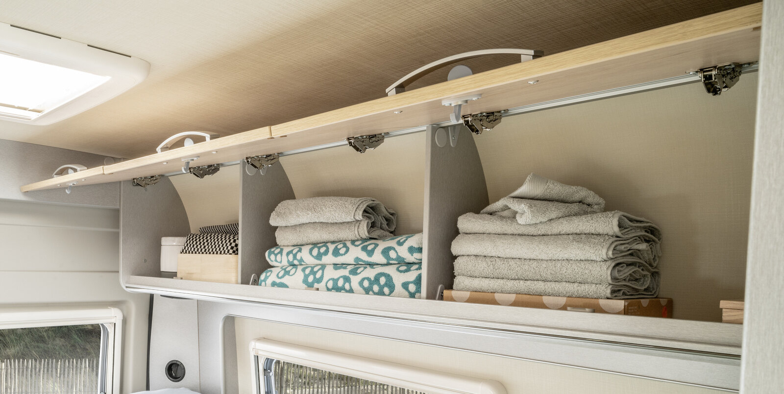 Pensili aperti sopra il letto posteriore che contengono asciugamani ed altri tessili; Free 540 HYMER